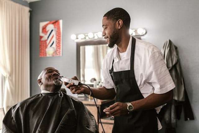 Barber using clippers to trim a client’s beard at Bay State Barbershop in Norwood, MA.